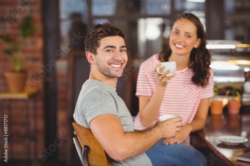 Smiling friends sitting and drinking coffee