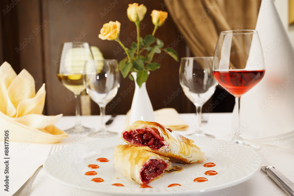 Cherry pie/Two slices of cherry pie in portion on a white plate in restaurant. Decorative restaurant table. Wine and flowers. Cherry pie/Two slices of cherry pie in portion on a white plate in restaurant. Decorative restaurant table. Wine and flowers.