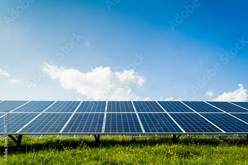 Solar panels on green field and blue sky