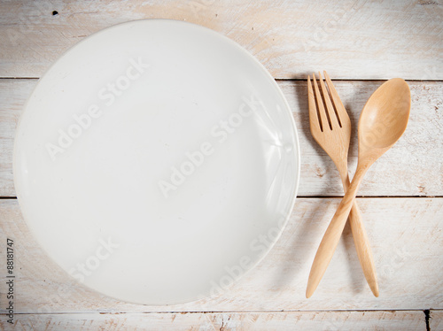 plate with fork and spoon on wood  with shadows
