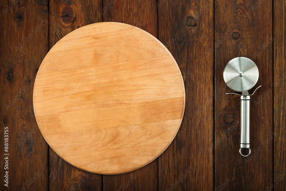 Steel pizza cutter at wooden background Steel pizza cutter at wooden background