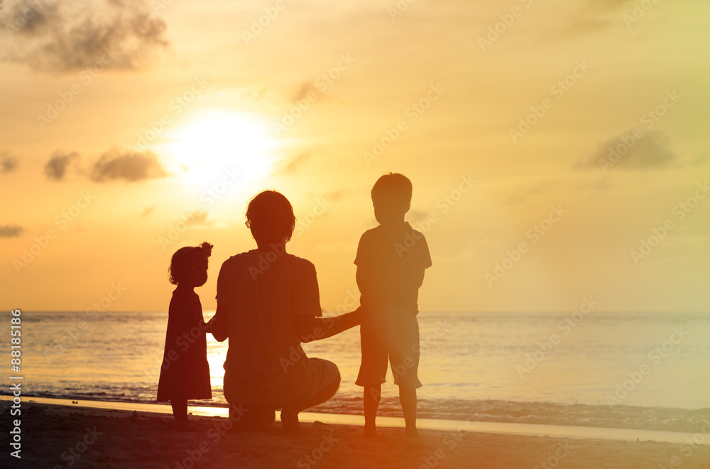 father with two kids at sunset beach