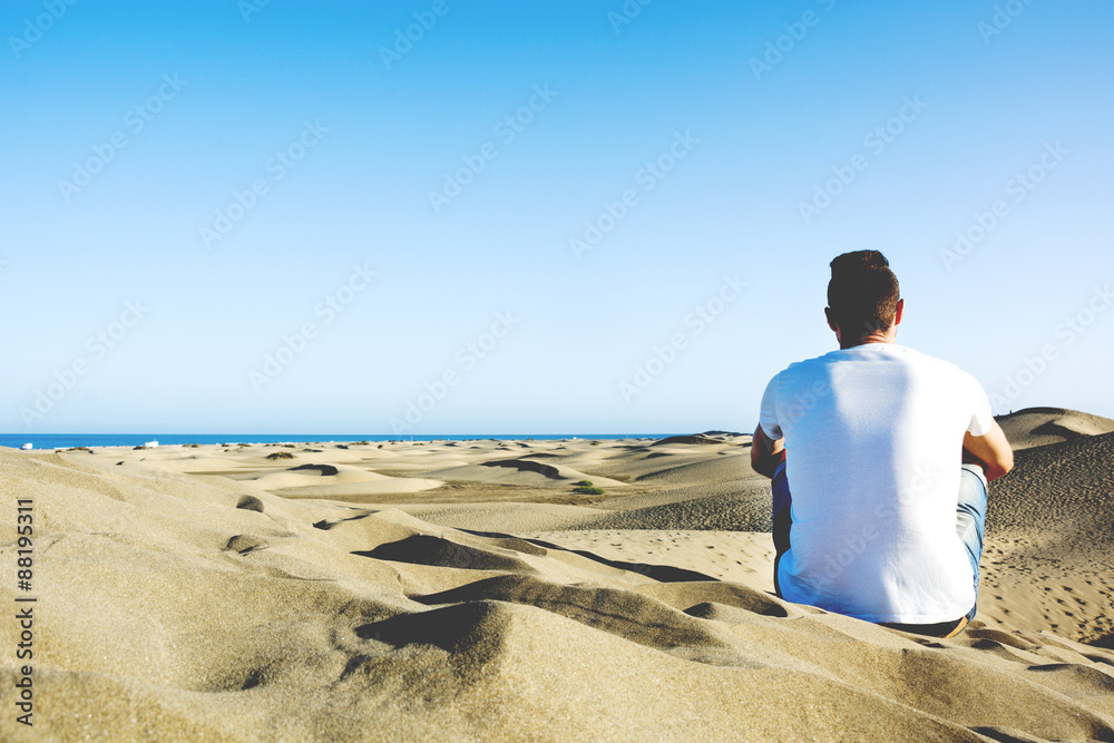 Young man sitting on a dune