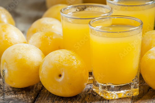 Delicious fresh juice of yellow sweet plums in a glass on the ol