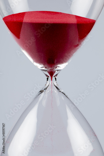 Red sand in an hourglass, vertical