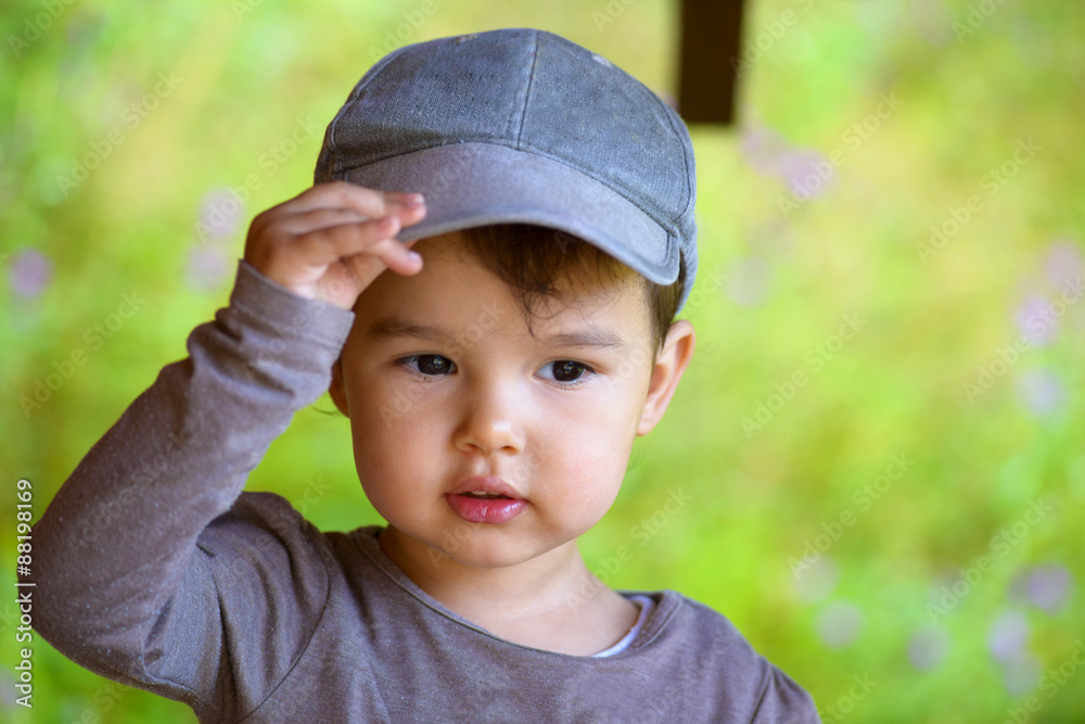 Little girl putting on her hat in summer time Little girl putting on her hat in summer time