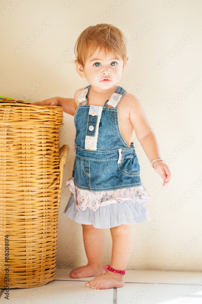 hübsches Baby im Jeanskleid stützt sich ab Stock-Foto | Adobe Stock
