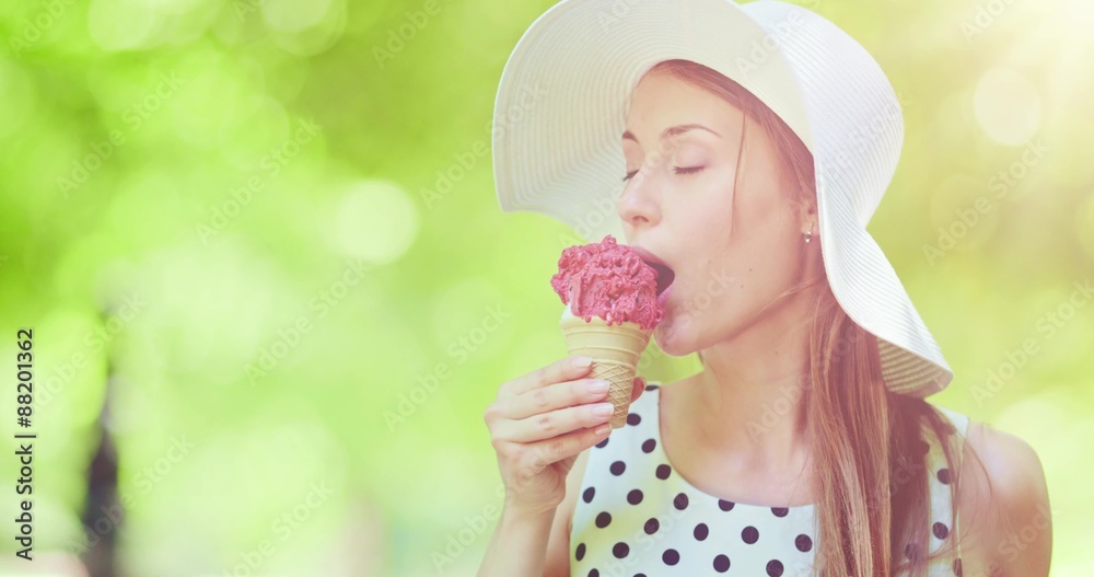 Beautiful woman eating ice cream in the park. Slow motion, portrait. Stylish young attractive woman in white hat enjoying tasty ice cream and nature in the green sunny summer outdoors. 4K, DCi. Beautiful woman eating ice cream in the park. Slow motion, portrait. Stylish young attractive woman in white hat enjoying tasty ice cream and nature in the green sunny summer outdoors. 4K, DCi.