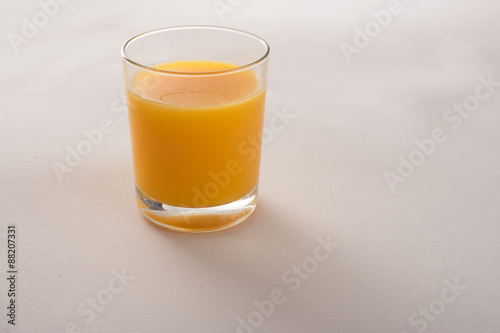 orange juice in a glass on beige fabric background 