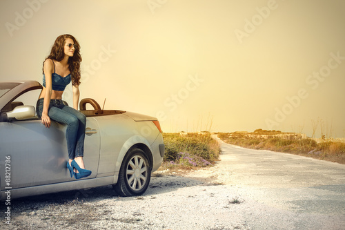Girl sitting on a car in the countryside