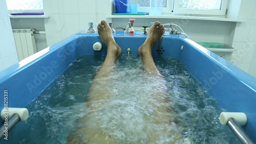 Man lies in the treatment bath in a spa, bath with oxygen and herbs
