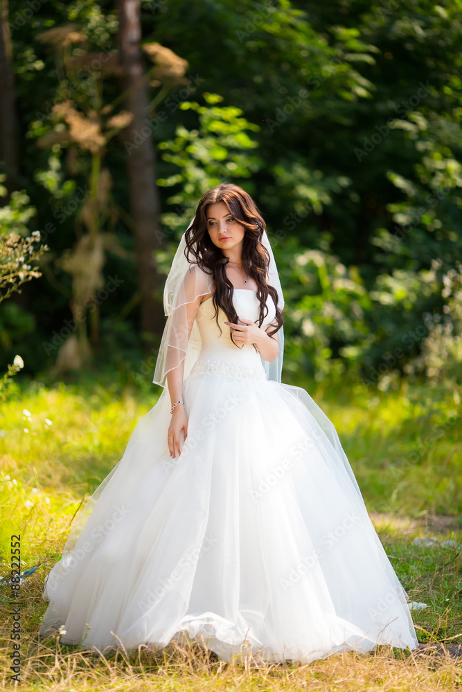 Wedding picture of happy brunette bride outside.