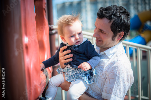 Image of cute little daughter in young dad's hands