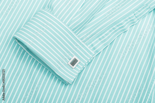 Sleeve of a striped turquoise shirt with a cuff link isolated on white background