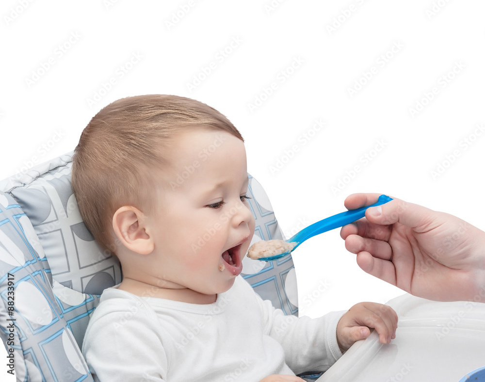 The father feeds with porridge of the one-year-old kid, isolated on the white The father feeds with porridge of the one-year-old kid, isolated on the white