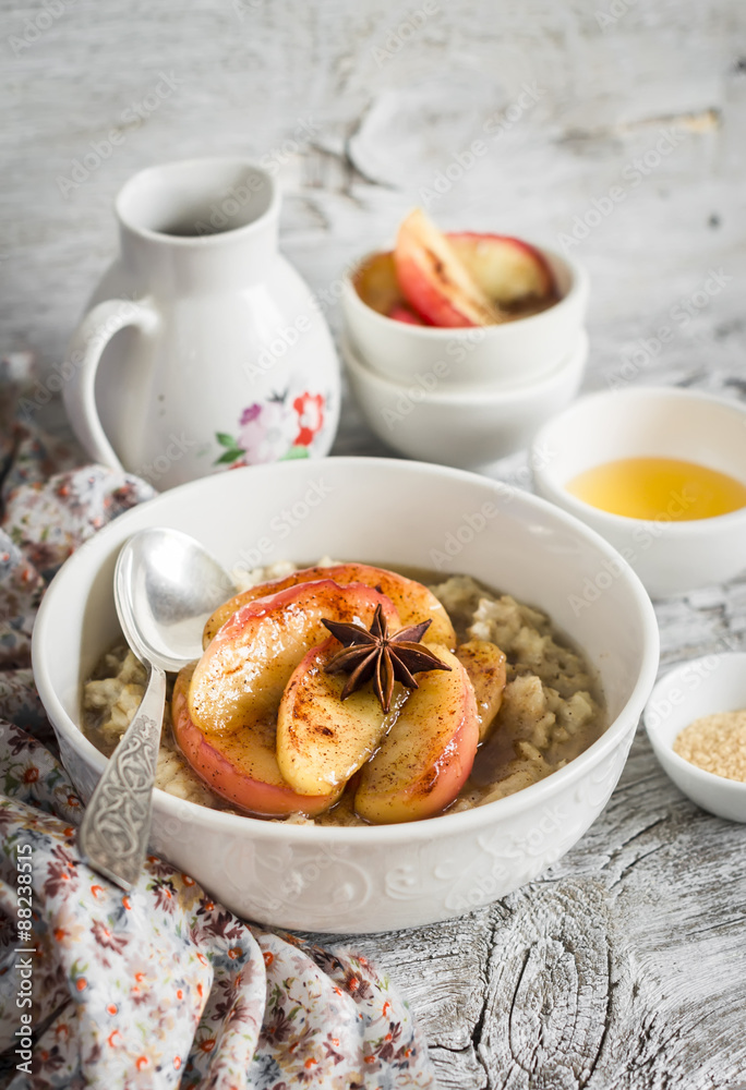 oatmeal with caramelized apples and cinnamon in a white bowl on a light wooden background - healthy Breakfast