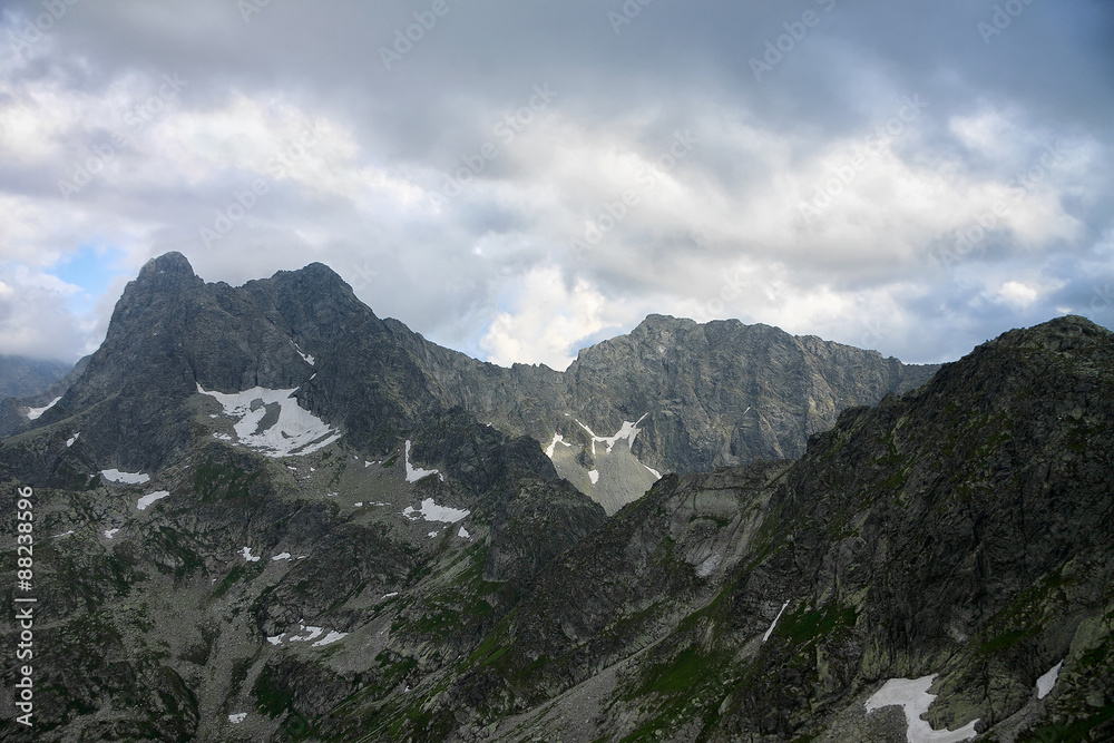 Severe rocky peaks of mountains under cloudy sky 