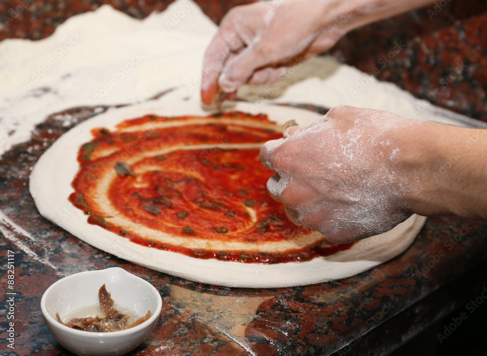 Chef preparing pizza on marble table, closeup