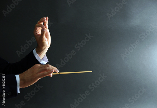 Music conductor hands with baton on black background photo