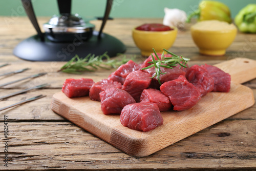 carne cruda manzo tagliato a cubi su tagliere sfondo legno rustico photo