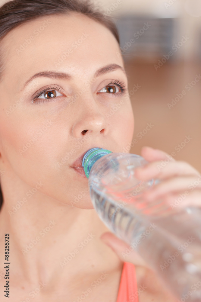 Young sportswoman drinking water after training Young sportswoman drinking water after training