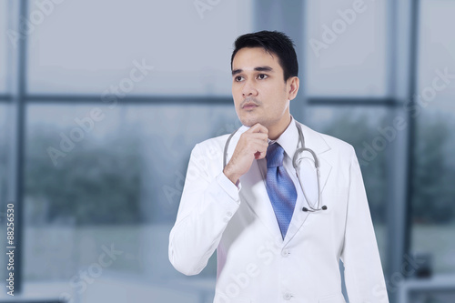 Thoughtful doctor with hand on chin