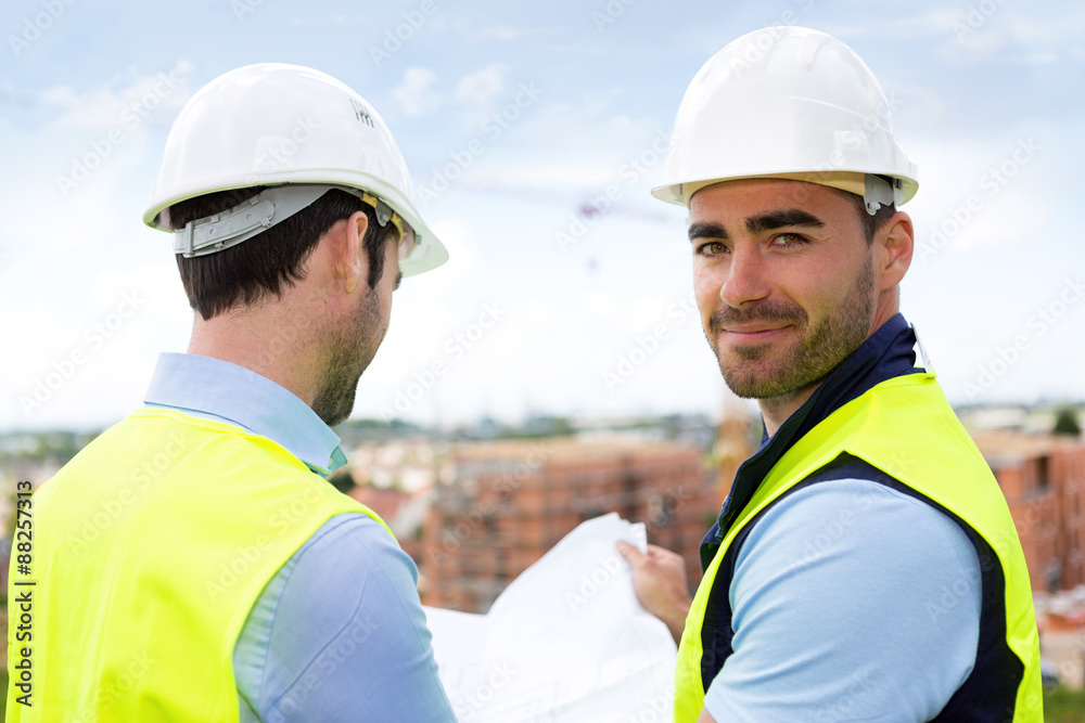 Engineer and worker watching blueprint on construction site Engineer and worker watching blueprint on construction site
