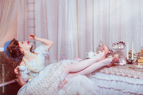 Indoors shot in the Marie Antoinette style. Woman eating red cherry. photo