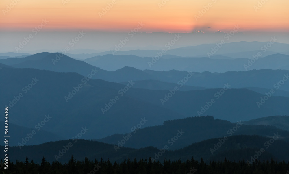 Distant mountain range and thin layer of clouds on the valleys