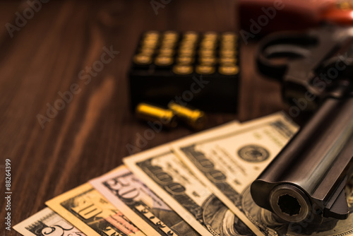 Revolver with a bundle of money on a wooden table