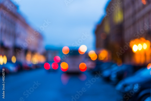The bright lights of the evening city, the street going cars. Defocused image