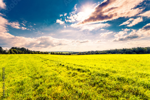 Sun comes out of cumulus clouds and illuminates a fields