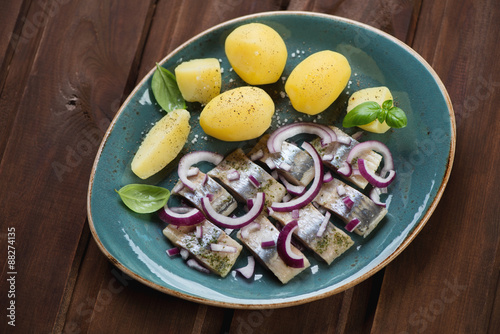 Sliced herring fillet served with red onion and boiled potato