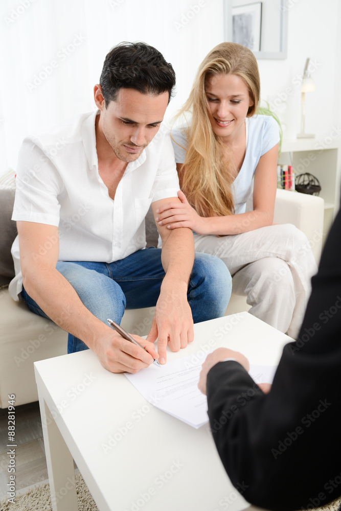 happy young couple at home in transaction signing contract with a business woman happy young couple at home in transaction signing contract with a business woman