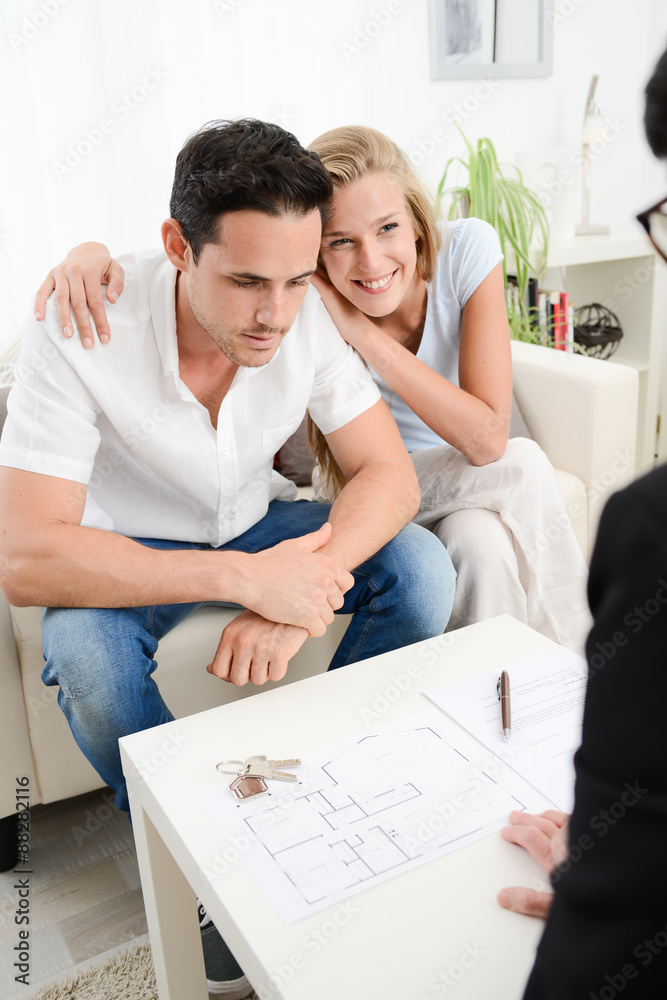 happy young couple at home with blueprint in discussion with a business woman happy young couple at home with blueprint in discussion with a business woman