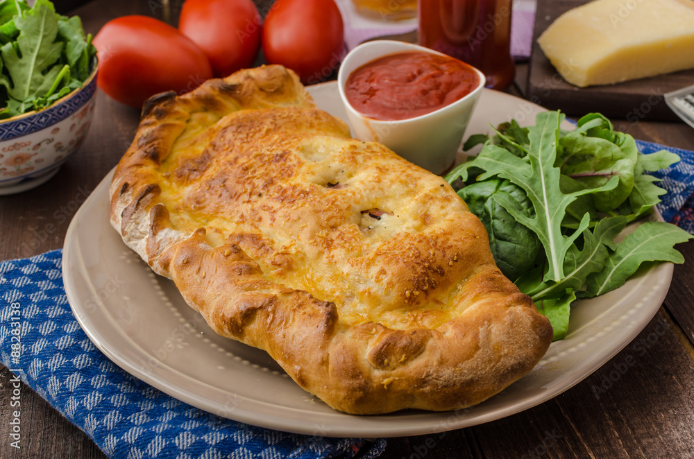 Calzone pizza stuffed with cheese and prosciutto Calzone pizza stuffed with cheese and prosciutto