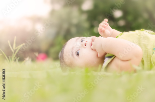 Little baby boy lying on  green grass in natural daylight outdoor