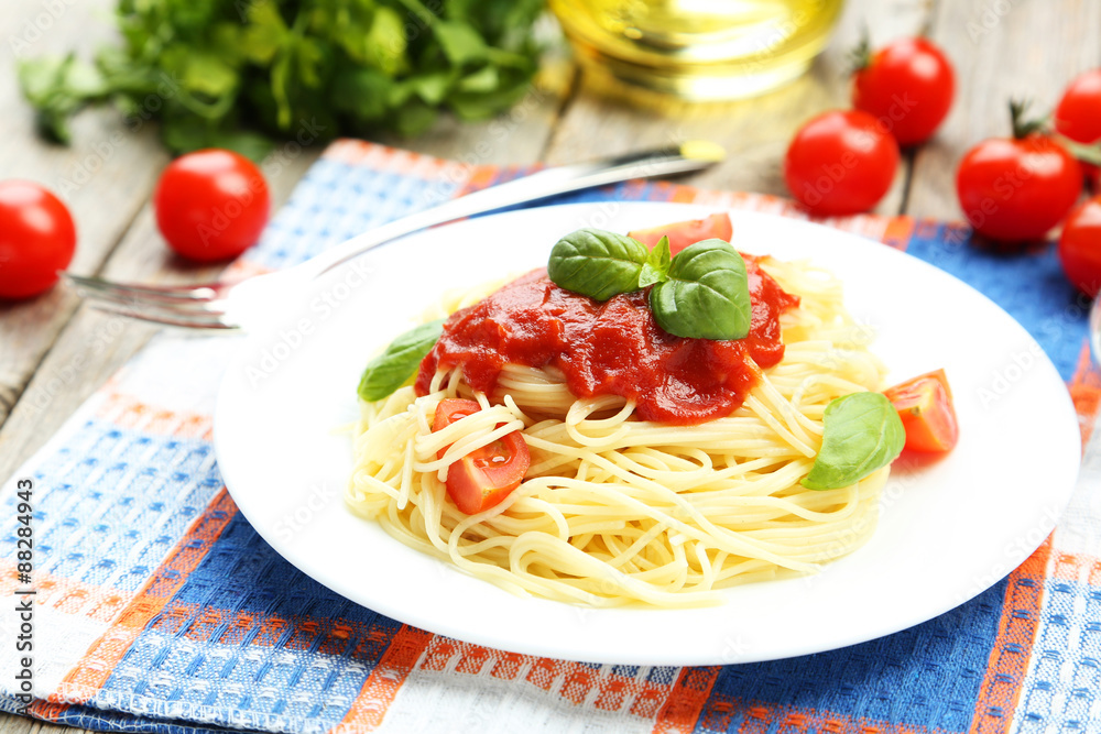 Spaghetti with tomatoes and basil on plate on grey wooden backgr Spaghetti with tomatoes and basil on plate on grey wooden backgr