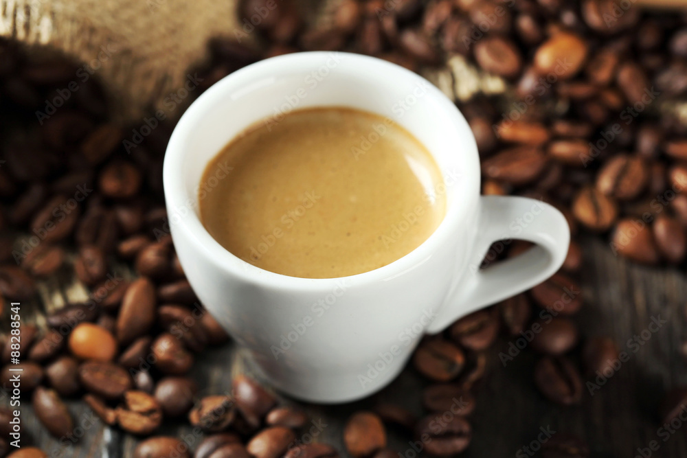 Cup of coffee with beans on table close up Cup of coffee with beans on table close up