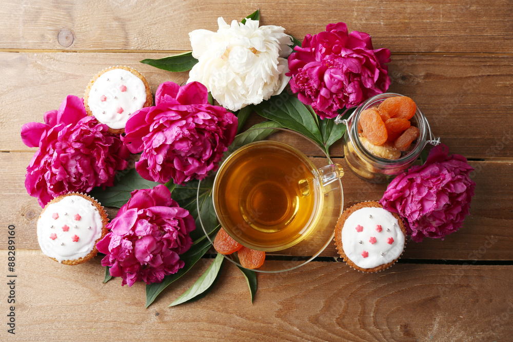 Composition with cup of herbal tea and peony flowers on wooden background Composition with cup of herbal tea and peony flowers on wooden background