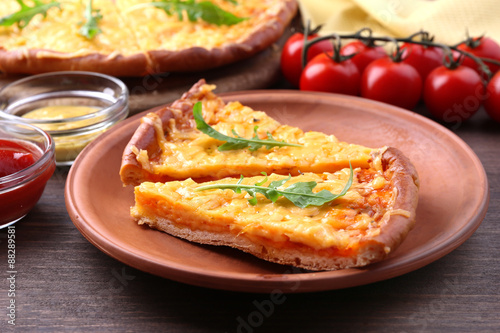 Slices of tasty cheese pizza with arugula and vegetables on table close up
