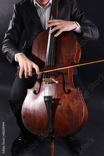 Man playing on cello on dark background