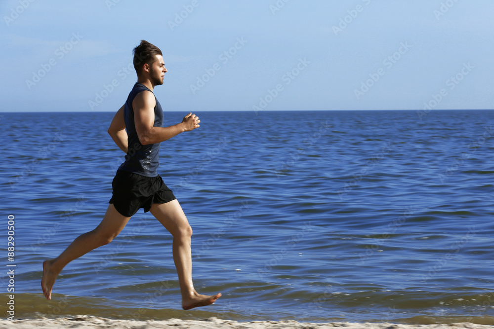 Naklejka premium Young man jogging on beach