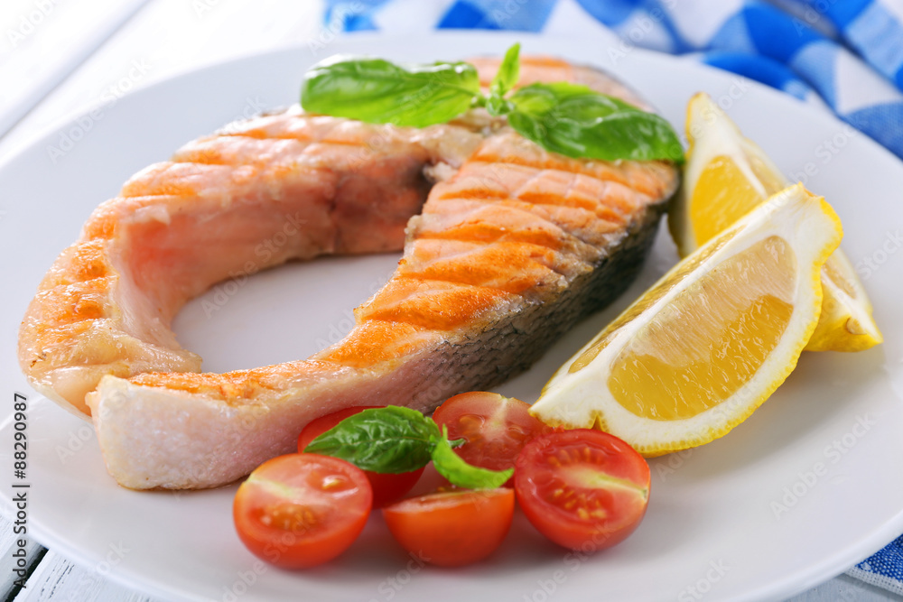 Tasty grilled salmon with tomato and lemon on table close up Tasty grilled salmon with tomato and lemon on table close up