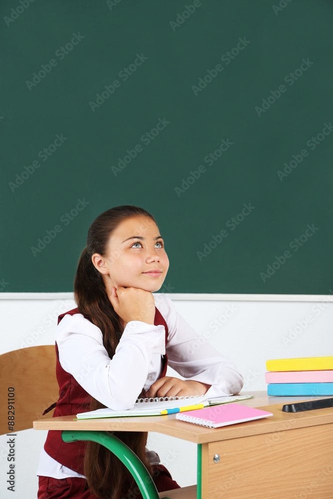 Beautiful little schoolgirl in classroom near blackboard Beautiful little schoolgirl in classroom near blackboard