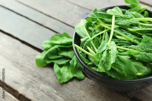 Bowl of fresh spinach leaves on wooden background