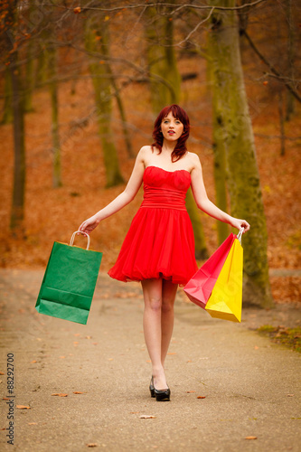 autumn shopper woman with sale bags outdoor in park