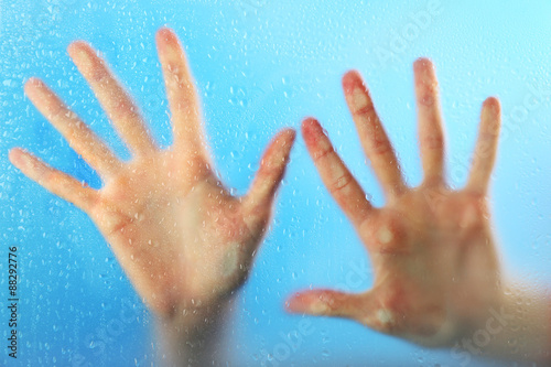 Female hands behind wet glass, close-up