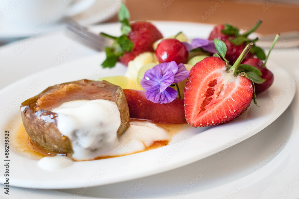 Warm, spicy baked apple with honey caramel sauce and bulgarian yoghurt, and fresh fruit decorated with edible purple flowers. Regional cuisine with a modern twist. Served in bed and breakfast inn. Warm, spicy baked apple with honey caramel sauce and bulgarian yoghurt, and fresh fruit decorated with edible purple flowers. Regional cuisine with a modern twist. Served in bed and breakfast inn.