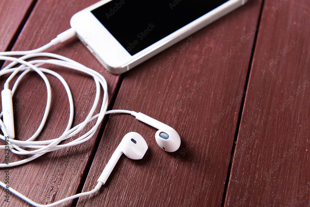 Mobile phone and earphones on wooden background Mobile phone and earphones on wooden background